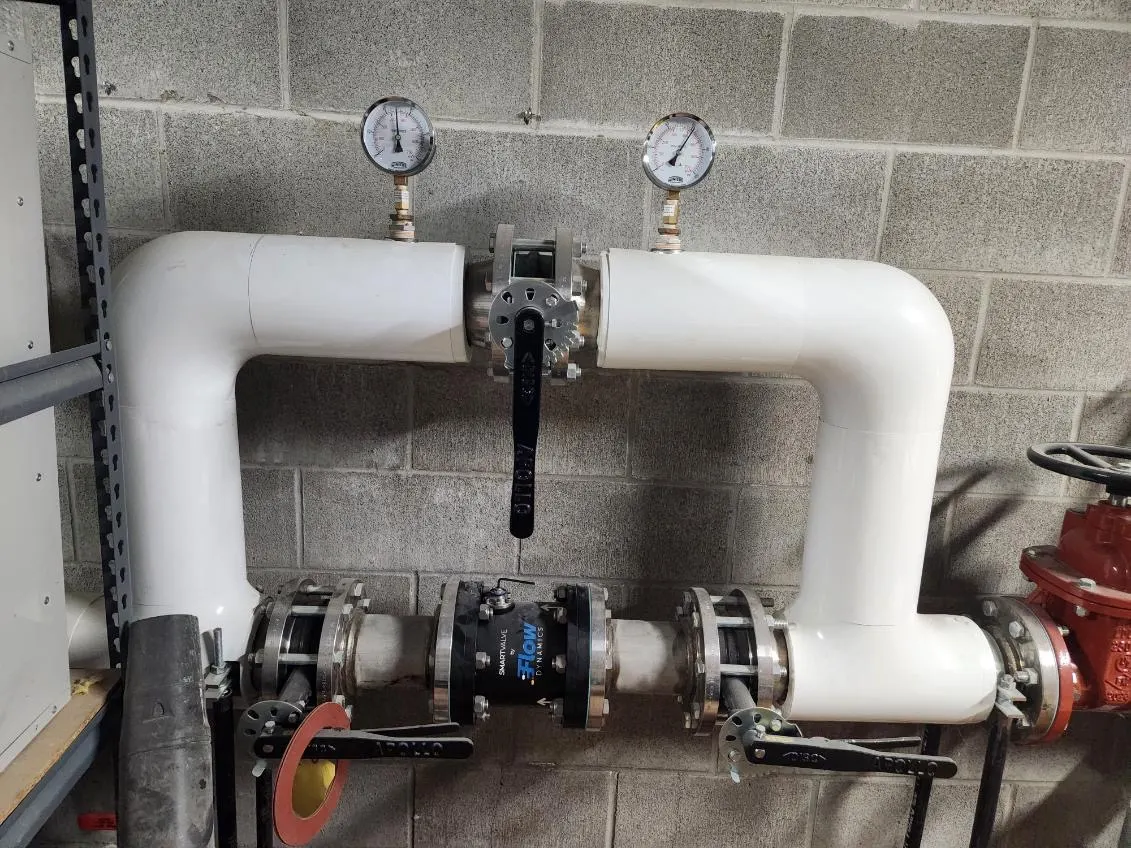 Smart Valve installed in a mechanical room with white insulated piping, pressure gauges and isolation valves